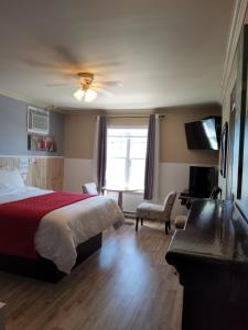 a hotel room with a bed and a desk and a window at Petit Hôtel Amara in La Malbaie