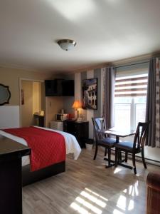 a hotel room with a bed and a table and chairs at Petit Hôtel Amara in La Malbaie