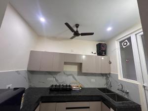 a kitchen with white cabinets and a ceiling fan at Sukhhin Chandigarh in Zirakpur
