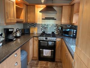 a kitchen with wooden cabinets and a stove top oven at Bramble Lodge in West Chevington +3 photos