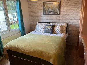 a bed in a bedroom with a brick wall at Bramble Lodge in West Chevington