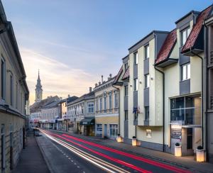 an empty city street with a clock tower in the background at City Hotel Stockerau in Stockerau