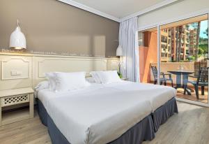 
a hotel room with a large bed and a large window at H10 Mediterranean Village in Salou
