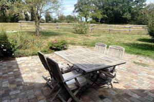 a wooden table with four chairs and a fence at La Maison de Fougerolles, Renovated farmhouse in Fougerolles