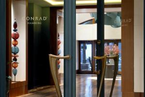 a pair of chairs in a room with glass doors at Conrad Hamburg in Hamburg