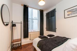 a bedroom with a bed and a mirror and a window at Cobb's Margate Old Town Hideaway in Margate