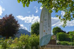 a banner hanging from a tree with mountains in the background at Affittacamere ai 4 venti in Arta Terme +2 photos