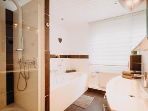 a bathroom with a shower and a tub and a sink at Hillside Braunlage in Braunlage +16 photos