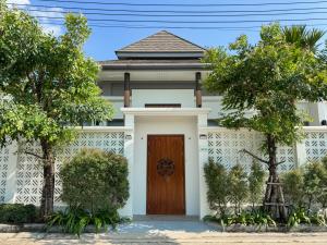 a white house with a wooden door and trees at Luxury 3BR Pool Villa Private Pool Quiet Area in Ban Klang