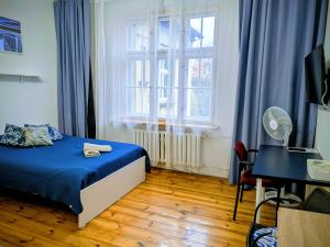 a bedroom with a bed with blue sheets and a window at Pokoje Rybnicka 10 in Katowice