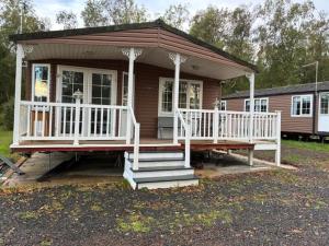 a small house with a white porch and stairs at Bramble Lodge in West Chevington