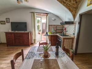 a kitchen with a table with chairs and a television at Dammuso Nuzzarè in Syracuse