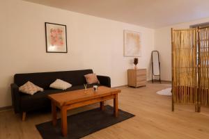 a living room with a black couch and a wooden table at Le Saint Regis - Hyper centre. in Le Puy-en-Velay