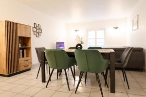 a dining room with a table and green chairs at Le Saint Regis - Hyper centre. in Le Puy-en-Velay
