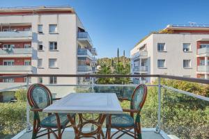 a table and chairs on a balcony with a building at Appart'hôtel Odalys City - Antibes Olympe in Antibes