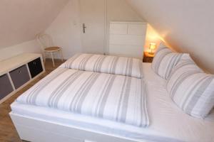 a white bed with striped sheets in a room at Ferienhaus Ostseebrise Usedom im Grünen familienfreundlich ruhig Parkplatz Terrasse Kamin in Karlshagen