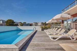 a row of lounge chairs next to a swimming pool at Appart'hôtel Odalys City - Antibes Olympe in Antibes