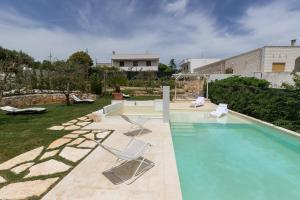 a swimming pool with two chairs and a house at Dimora San Quirico - b&b Cisternino Valle D'Itria in Cisternino