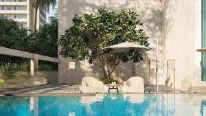 a pool with two chairs and an umbrella and a table at PureJoy Hotel Langkawi in Kuah