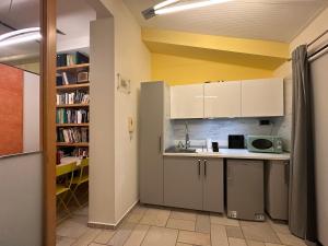 eine Küche mit weißen Schränken und einem Bücherregal in der Unterkunft Casa 65 in Pontedera