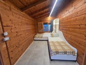 two beds in a room with wooden walls at Guest House Luiza in Borsh