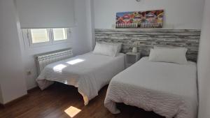 a bedroom with two beds and a brick wall at Ático Vista La Sierra in Jarandilla de la Vera