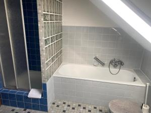 a bathroom with a white tub and blue tiles at Gästehaus Wildfein in Wilnsdorf