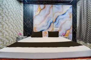 a bedroom with a large bed with a painting on the wall at Hotel O Royal Prayag in Prayagraj