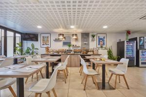 a restaurant with wooden tables and white chairs at Appart'hôtel Odalys City - Monaco Les Hauts de la Principauté in Beausoleil