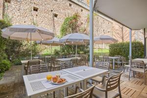 an outdoor patio with tables and chairs and umbrellas at Appart'hôtel Odalys City - Monaco Les Hauts de la Principauté in Beausoleil +86 photos
