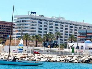 a boat in the water in front of a large building at Hotel Apartamentos Fuengirola private studio in Fuengirola