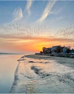 a beach with the sun setting in the background at Maison duplex centre plage port cabine in Le Crotoy