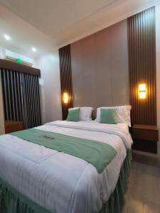 a bedroom with a large bed with green and white sheets at Bakom Inn Syariah in Bogor