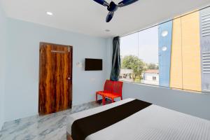 a bedroom with a bed and a window and a red chair at Super Hotel O MM Stay & Luxury Rooms in Hyderabad +23 photos
