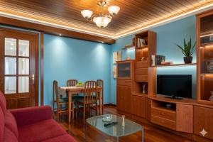 a living room with a couch and a table with a television at Apartamentos El Cuetu in Llanes