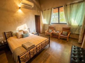 a bedroom with a bed and two chairs and a window at Enliven Homestay Alibag, Alibaug in Nagaon +101 photos