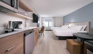 a hotel room with a bed and a kitchen at Hyatt Studios Harrisonburg in Harrisonburg