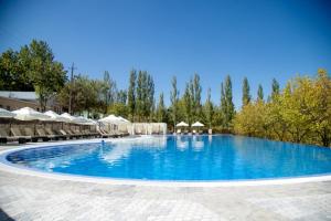 a large swimming pool with chairs and umbrellas at Avenue Park Hotel in Yusufkhona