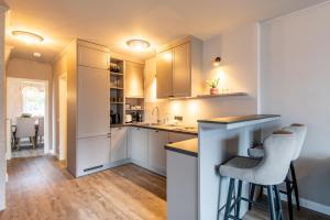 a kitchen with white cabinets and a bar with stools at Princessa Coast in Süderende