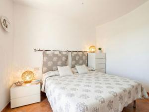 a white bedroom with a bed and a night stand at Apartment Mare 8 by Interhome in Porto Cervo