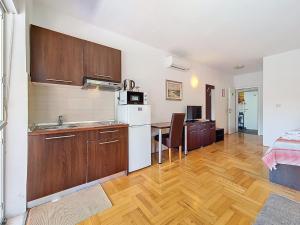 a kitchen with wooden cabinets and a wooden floor at Studio Rilić-1 by Interhome in Zaostrog
