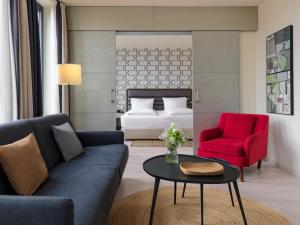 a living room with a couch and a red chair at H10 Berlin Ku'Damm in Berlin