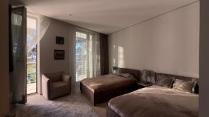 a bedroom with two beds and a chair and a window at Casa La Perla in Budva