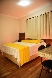 a bedroom with a bed with a yellow blanket on it at Hotel Volp Patos in Patos de Minas