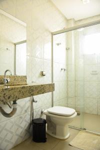 a bathroom with a toilet and a sink and a shower at Hotel Volp Patos in Patos de Minas +145 photos