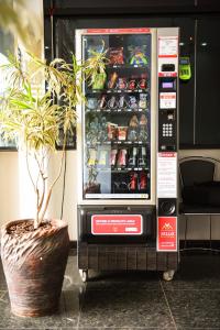 a soda vending machine with a potted plant next to it at Hotel Volp Patos in Patos de Minas