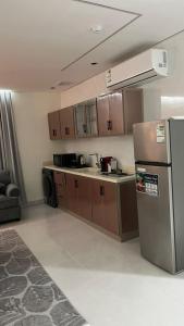 a kitchen with a stainless steel refrigerator and wooden cabinets at TwentyFour Seven Residence in Tabuk