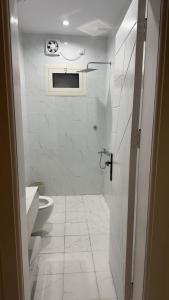 a white bathroom with a toilet and a window at TwentyFour Seven Residence in Tabuk +5 photos