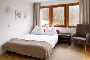 a hotel room with a bed and a chair and a window at Ferienwohnungen Vidoni in Bodensdorf