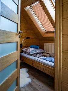 a bed in a wooden room with a window at Ostoja Urnica in Falsztyn